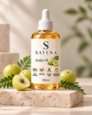 SAYENA Amla Oil 100ml bottle with botanical ingredients on an ivory stone display