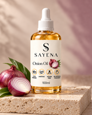 SAYENA Onion Oil 100ml bottle with red onions on an ivory stone display
